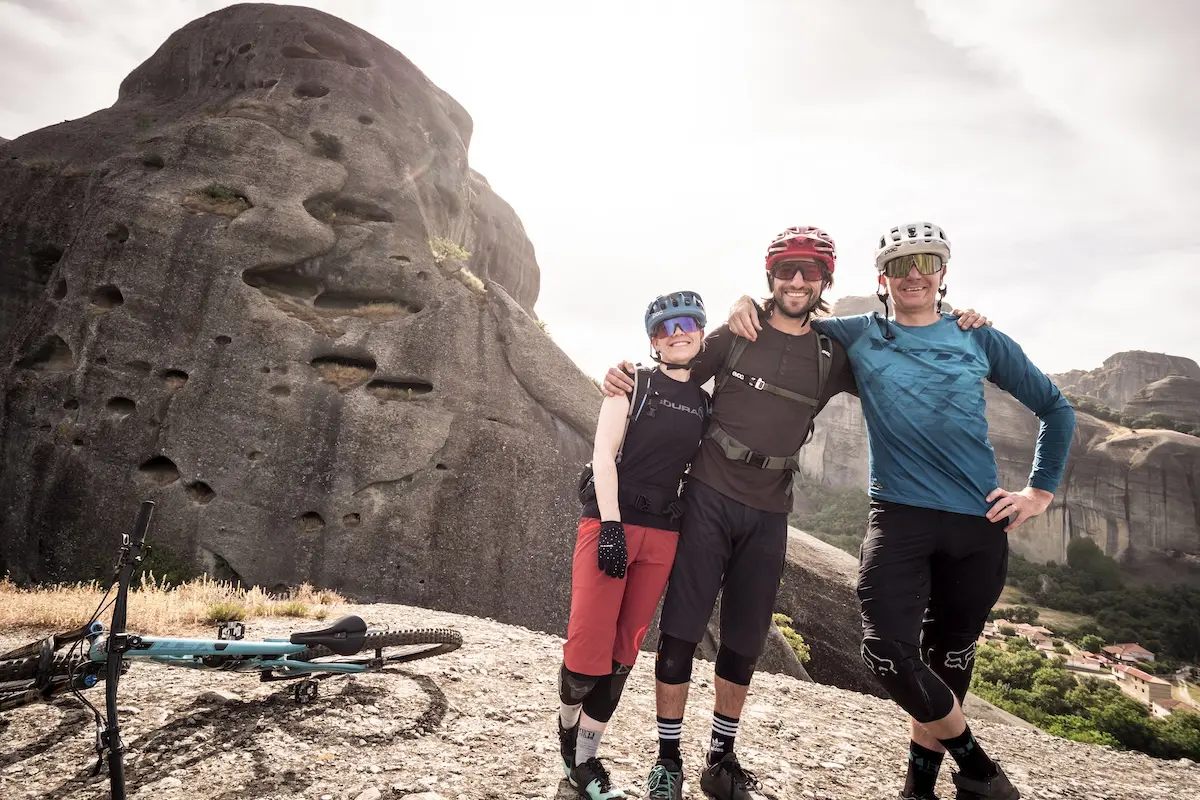 Male and female mountain bikers standing on a rock in Meteora, Greece
