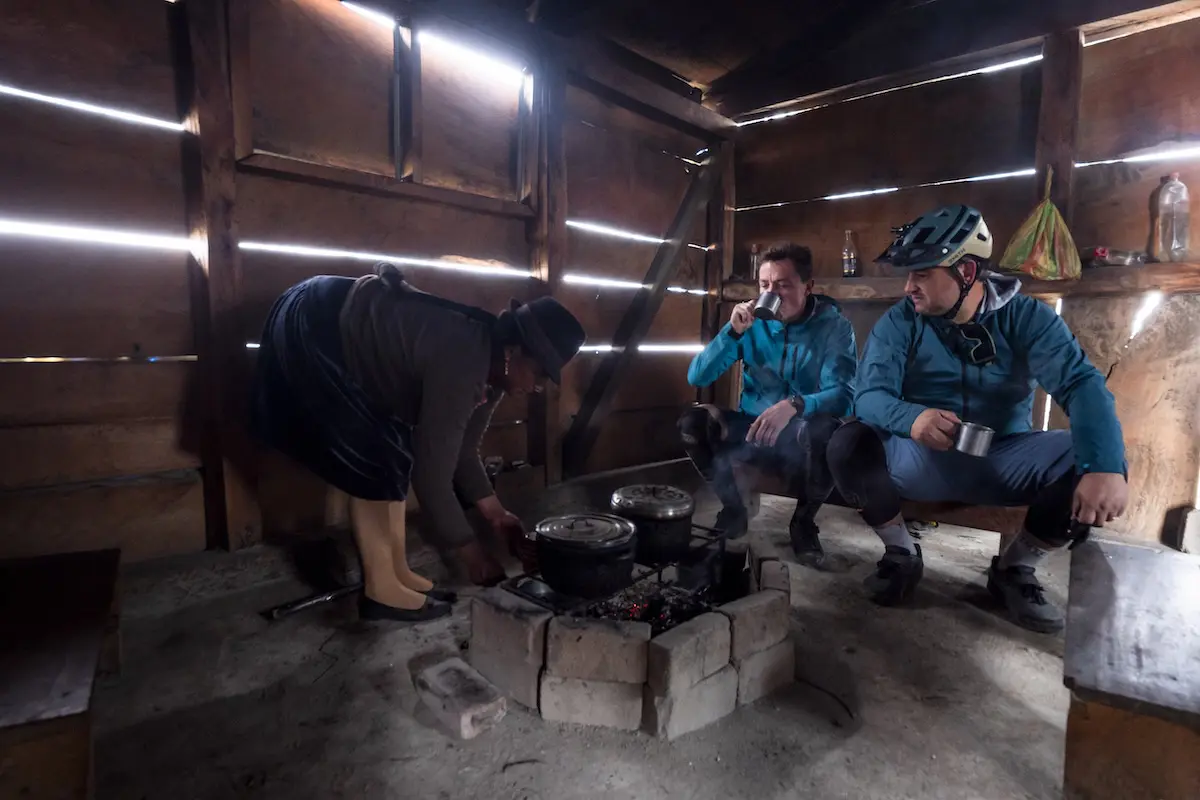Mountain bikers sharing tea with a local woman in Ecuador