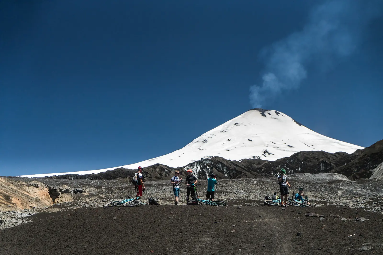 Mountain bikers in front of a smoking volcano