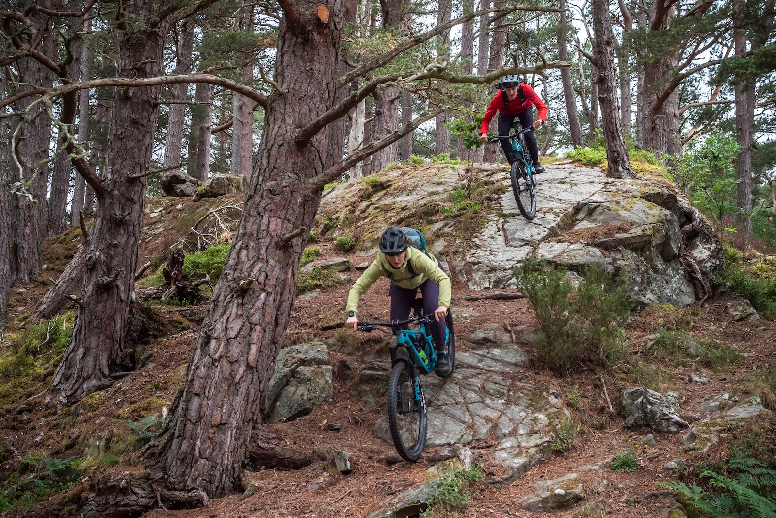 Male and female mountain bikers descending rocks in the Cairngorms Scotland