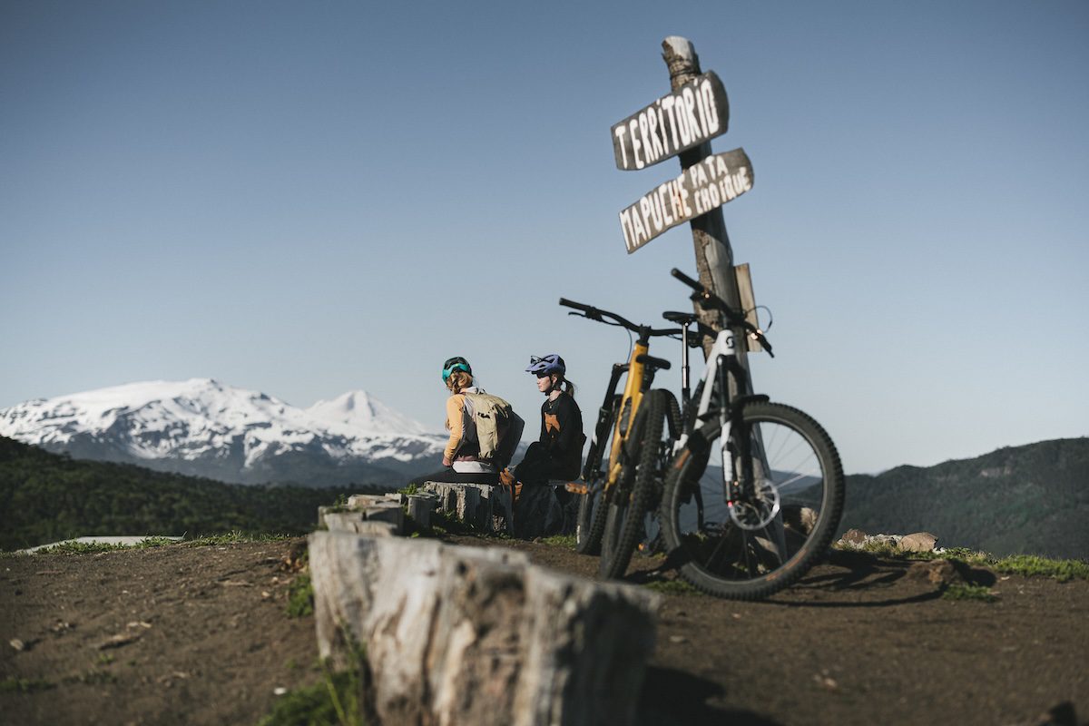 Female e-mountain bikers in Chile looking at snow-capped mountains
