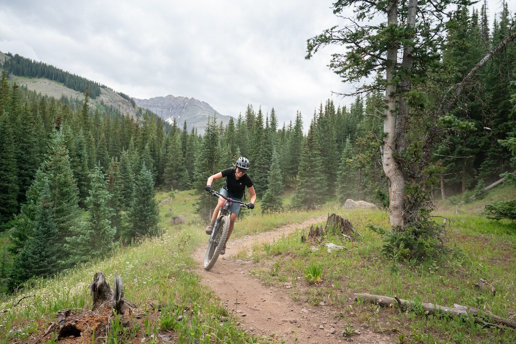 Female Yeti Freak riding in the fir trees in Colorado