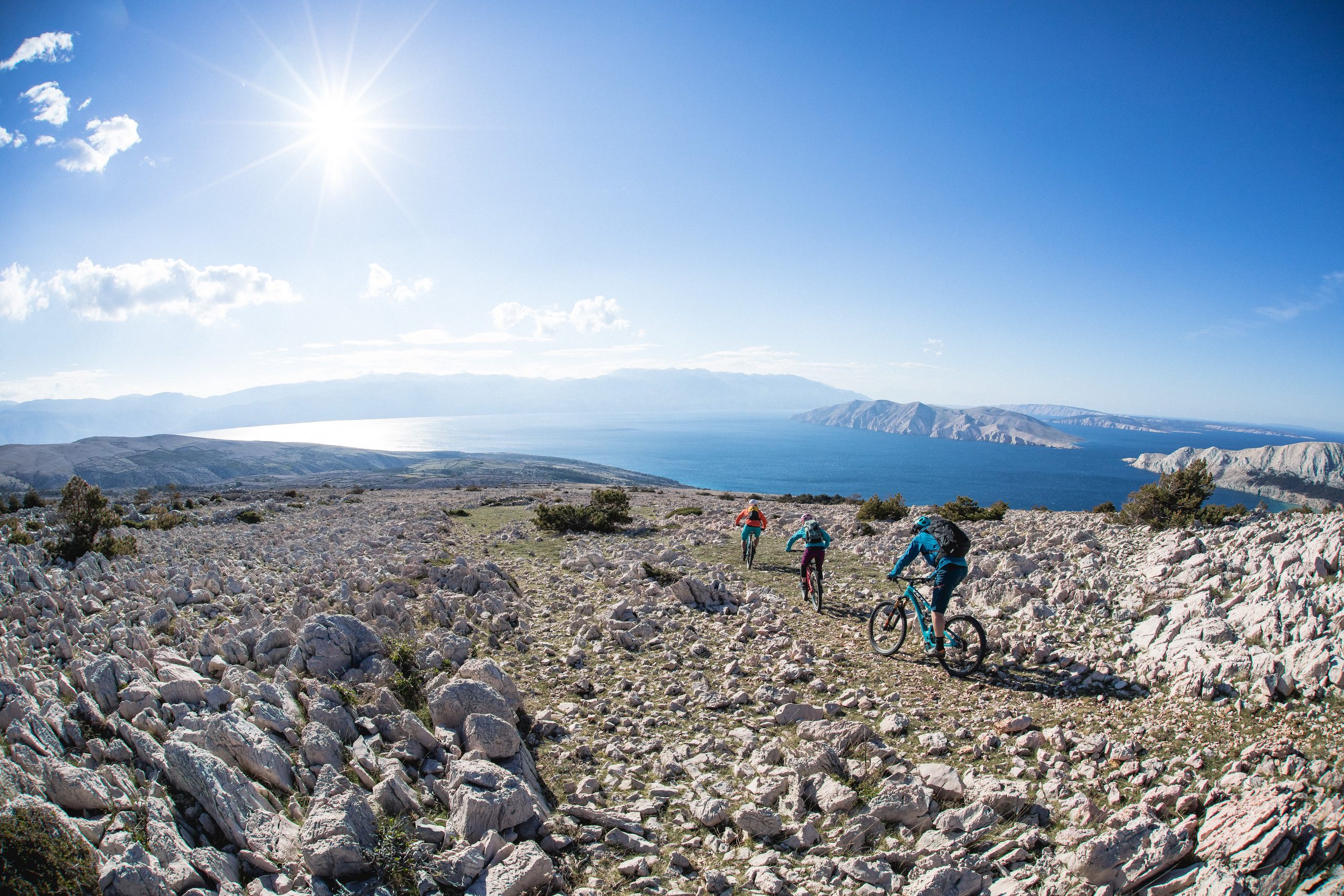 Mountain bikers descending on rocky terrain in sunshine in Croatia